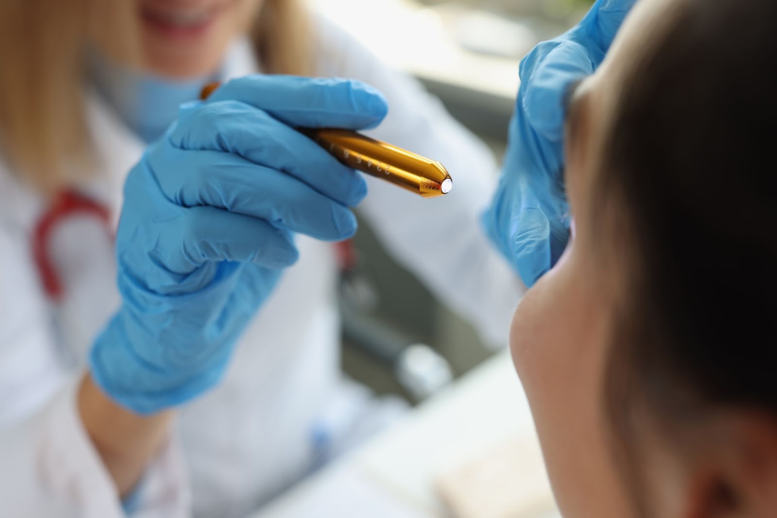 Eye doctor examining a patient's eye with a penlight.