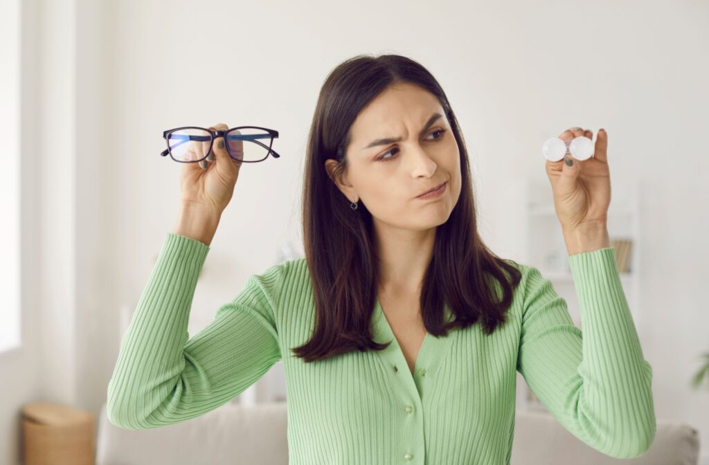 A person considers the difference between the glasses and contact lenses they're holding.