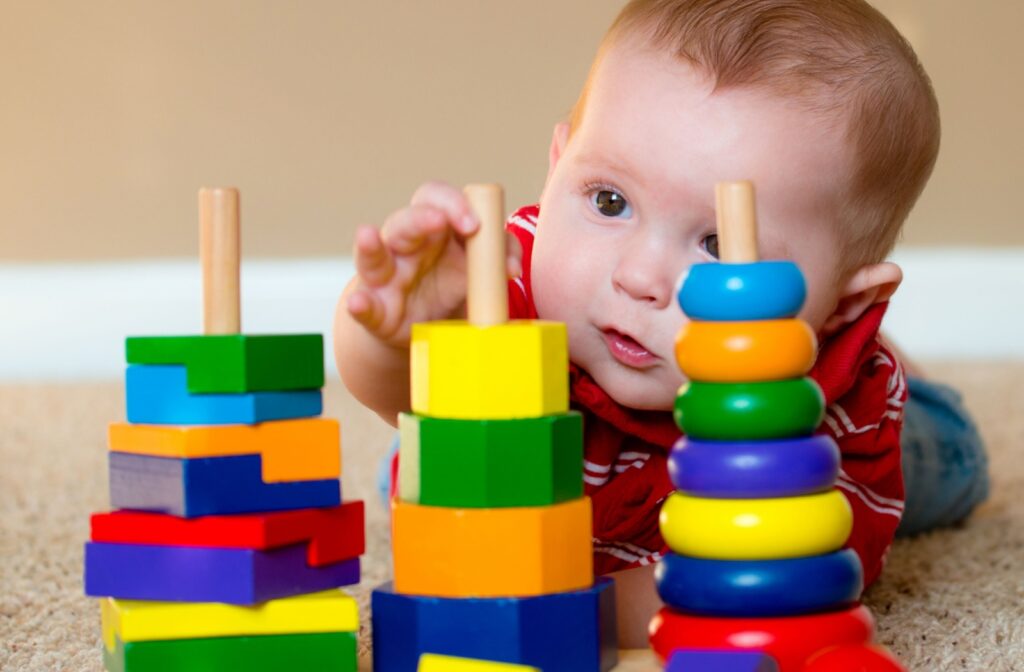 A baby gets some tummy time while playing with colourful blocks.