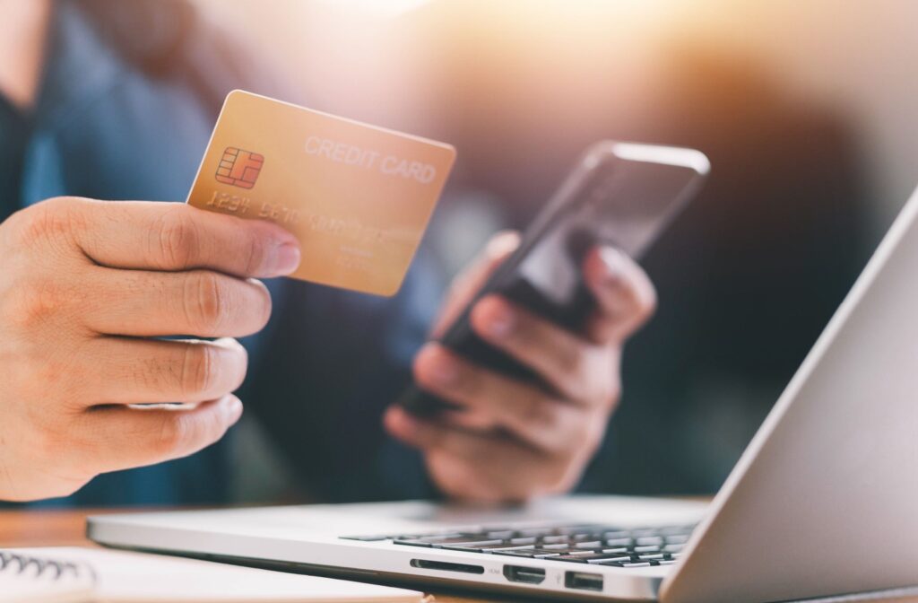 A person sitting in front of their laptop with a credit card in hand.